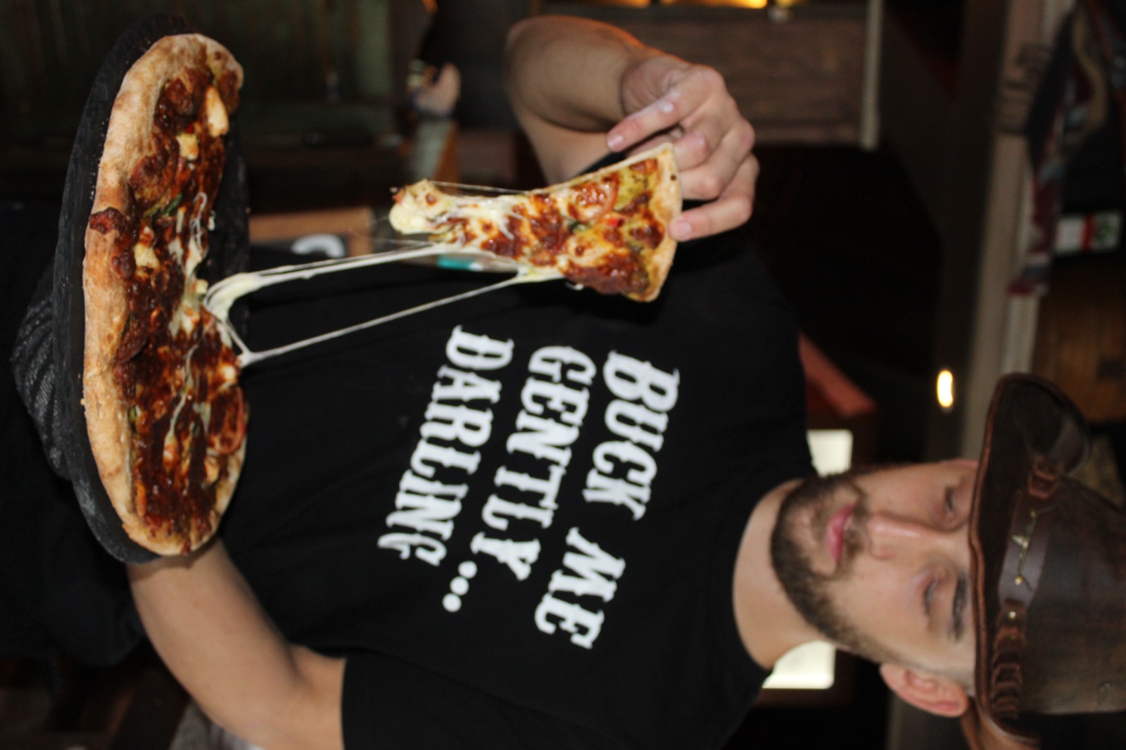 Guest in a Buck Me Gently Darling tee holding a wood-fired pizza