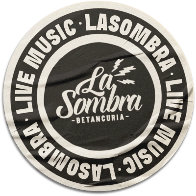 Circular black and white logo with the text 'La Sombra Betancuria' in the center, featuring three lightning bolts above. The outer ring repeats 'LA SOMBRA LIVE MUSIC' four times around the circle.