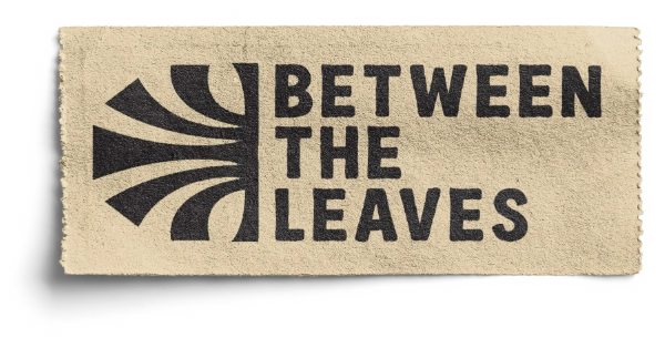 A beige ticket with a black abstract design on the left and the bold text 'BETWEEN THE LEAVES' stacked in three lines on the right.