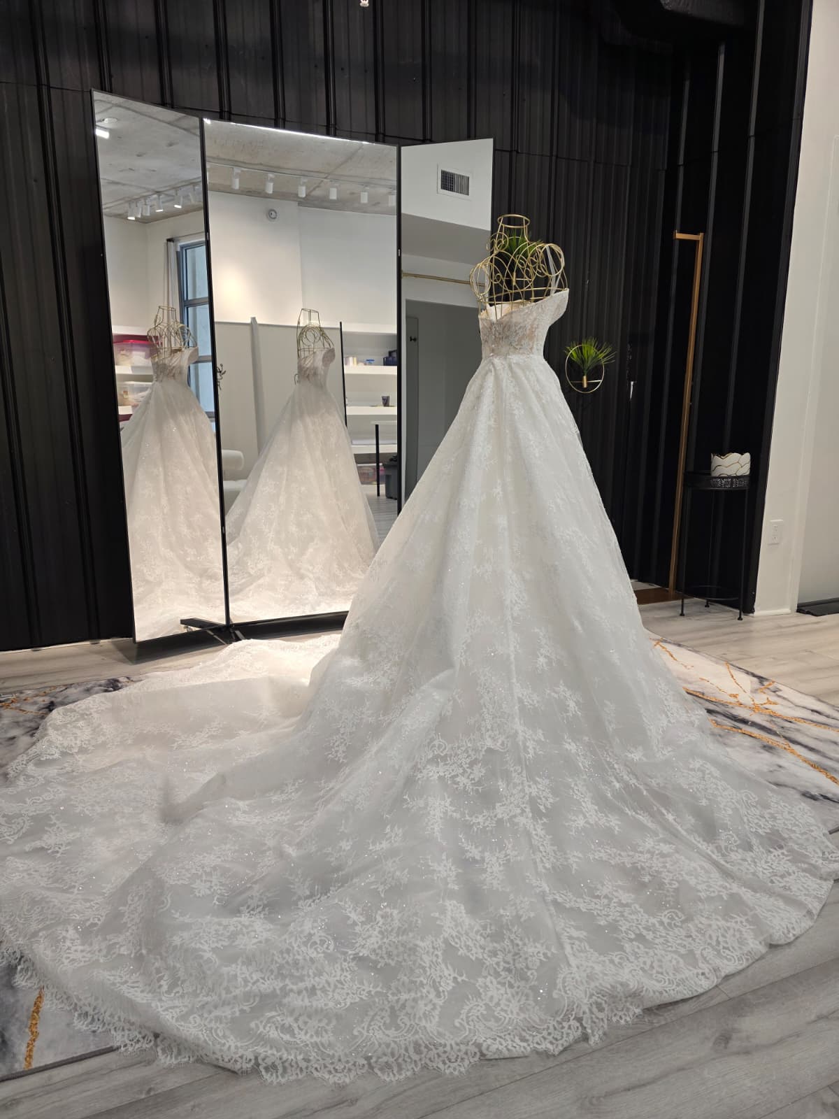 Bride in a flowing white gown holding a hand, walking along a city sidewalk and looking back smiling.