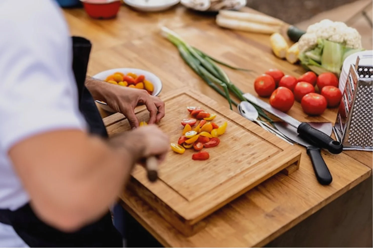 Close-up of chef preparing fresh vegetables, tomatoes, and greens on a wooden board