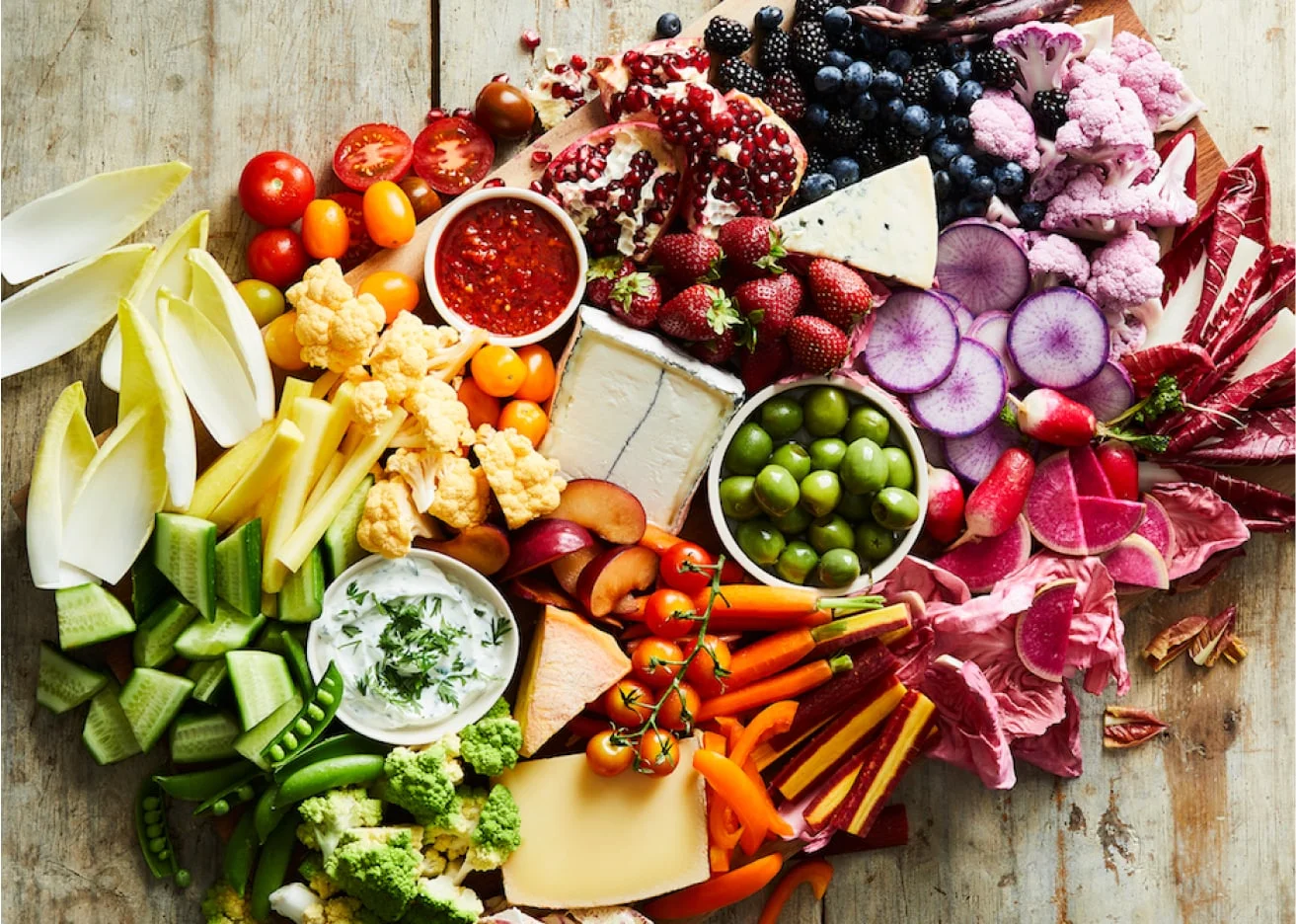 The Trio Platter featuring a mix of fresh vegetables, seasonal fruits, cheeses, and crackers.