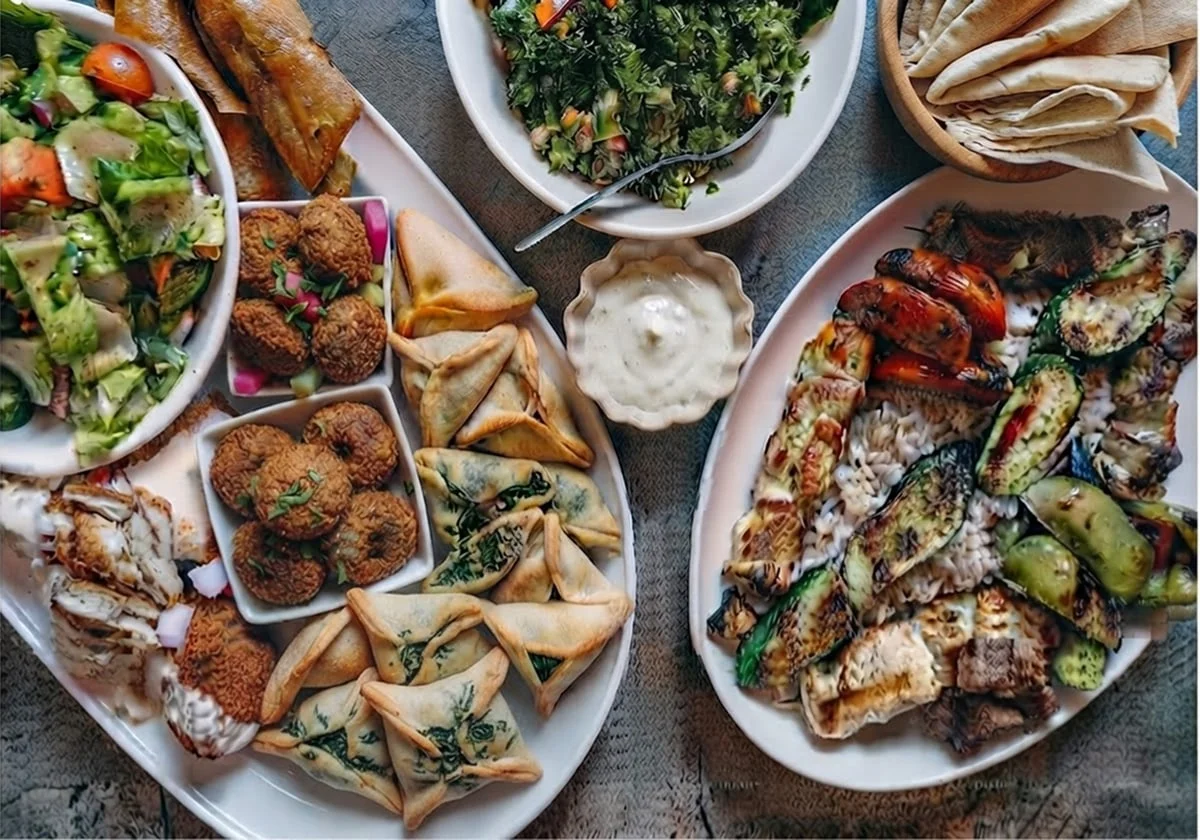 Lebanese catering platter with grilled chicken skewers, falafel, spinach fatayer, tabbouleh, and pita bread.