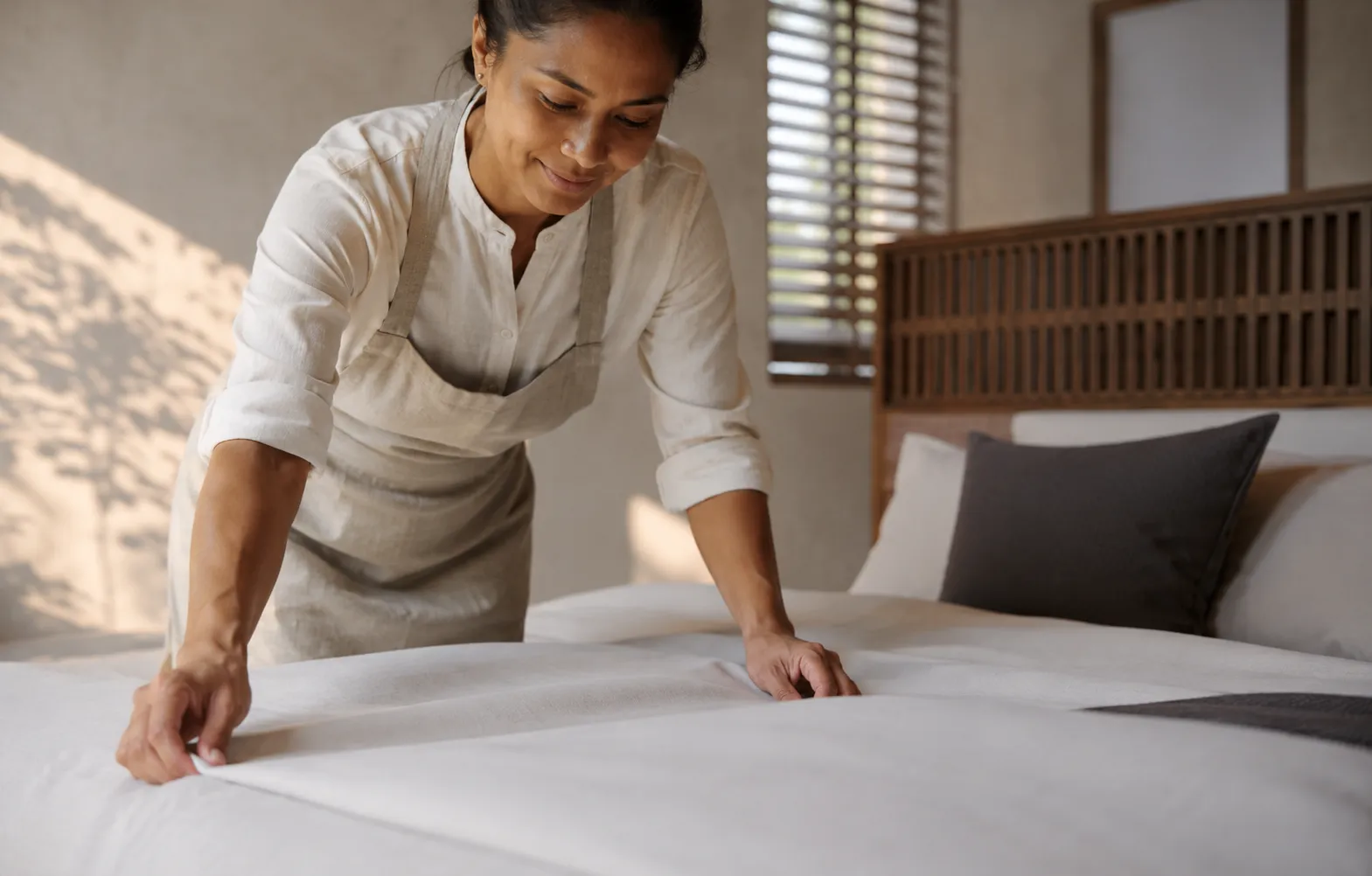 Housekeeper preparing a villa bedroom
