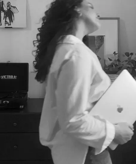 woman in white shirt holding laptop