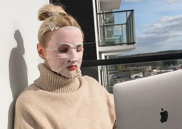Woman wearing a face mask while working on a laptop in the sun