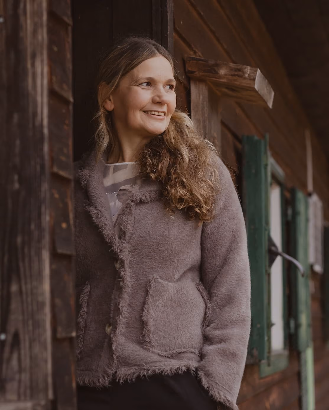 Silvia Braun lächelnd an einer Holzhütte