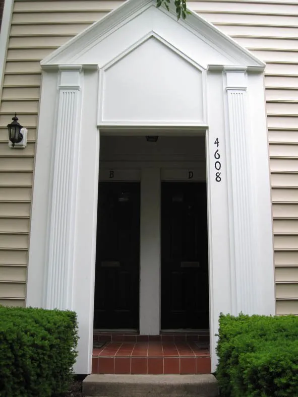 Tan vinyl siding surrounding a white pedimented entryway on a townhome