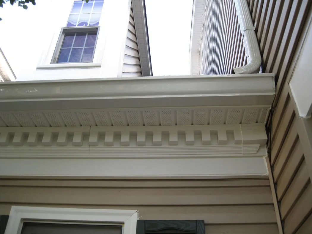 Dentil molding and cornice trim detail beneath the roofline of a sided home