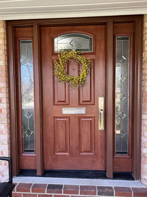 Mahogany-stained entry door with decorative glass sidelites and arched top lite