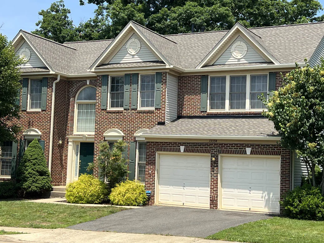 Gray architectural shingle roof with three front-facing gables on a brick colonial home