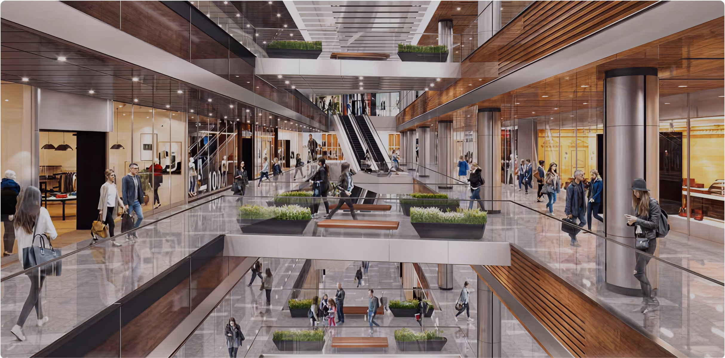 Modern multi-level shopping mall interior with glass railings, escalators, plants, and people walking.