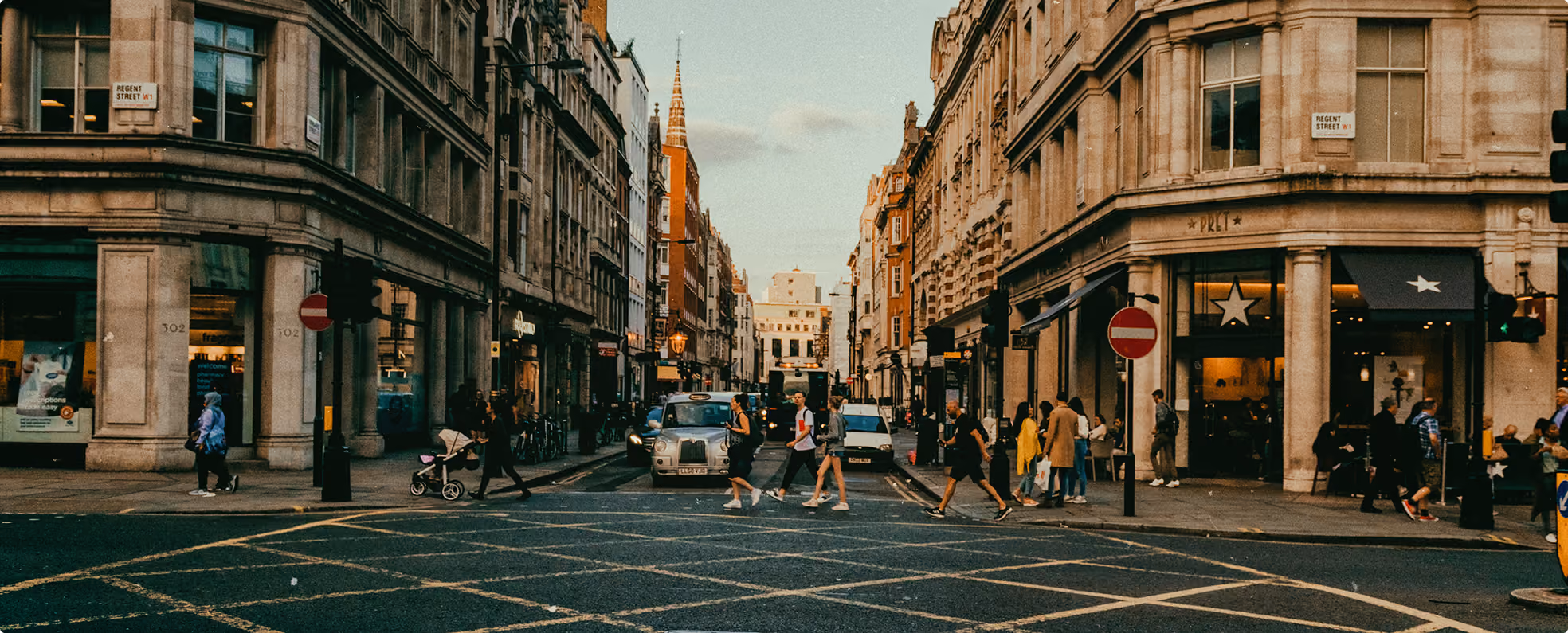 People crossing busy Regent Street intersection with classic buildings and shops in the background.