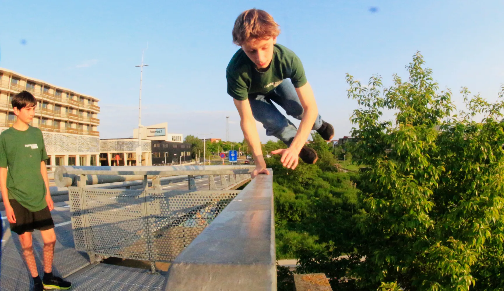 Jongere springt over een reling op een dakterras