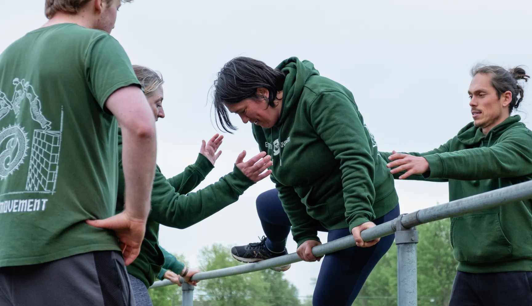 Volwassenen trainen samen aan een reling tijdens een outdoor training