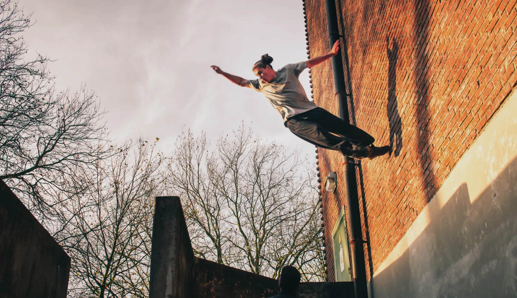 Parkourbeoefenaar springt tussen twee bakstenen gebouwen