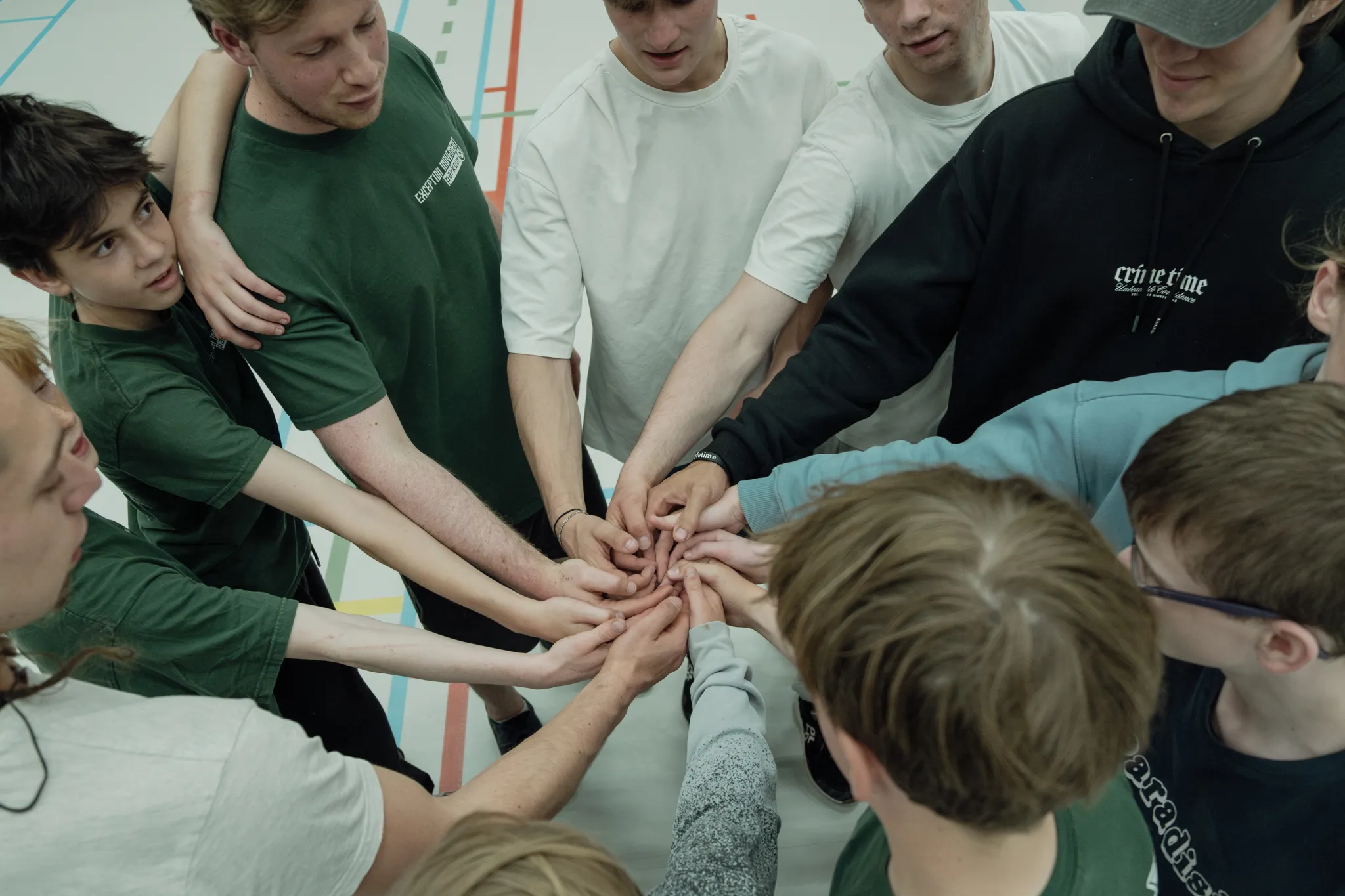 Jongeren steken hun handen samen in een teamcirkel