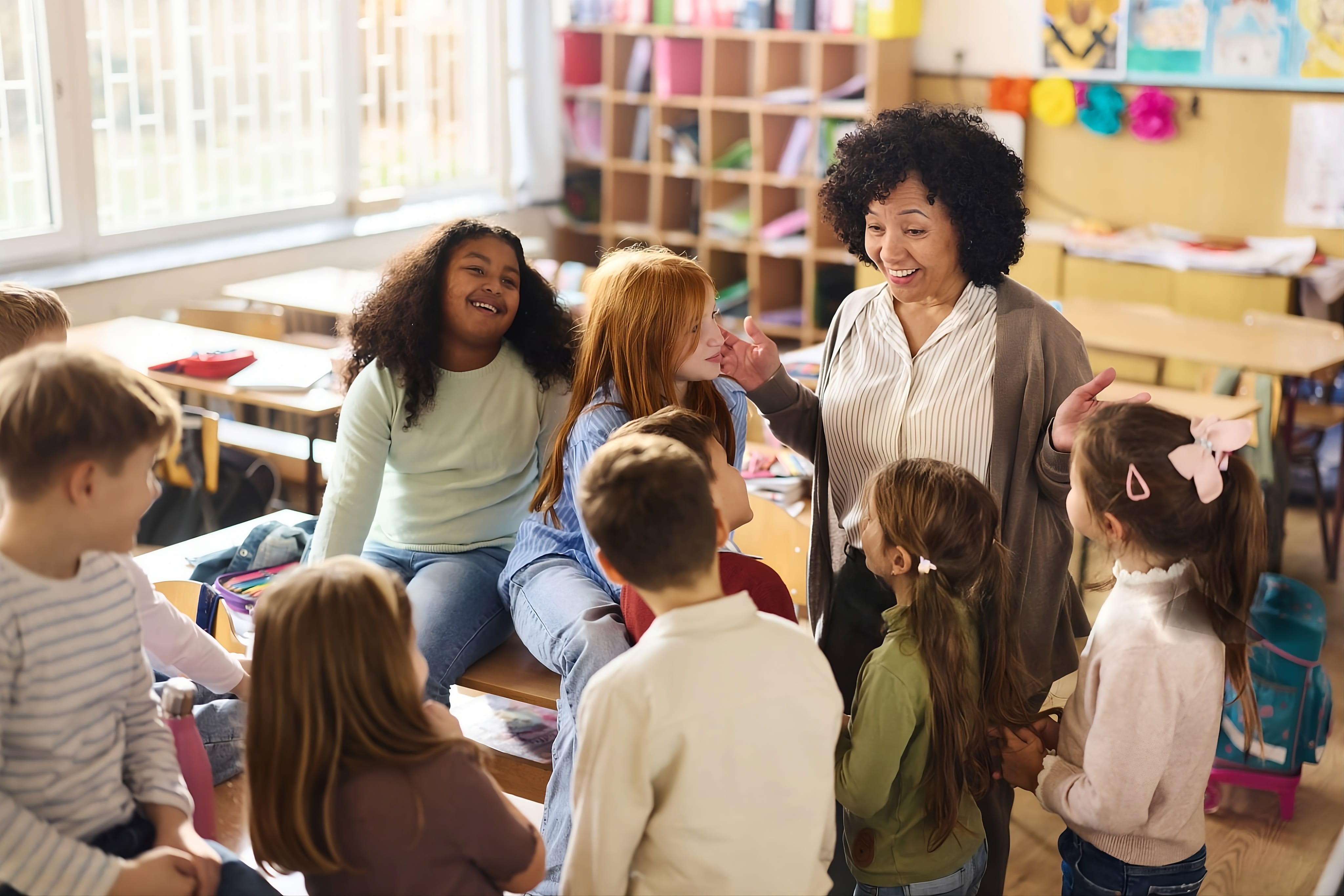 Respire Education | Teacher engaging happily with a group of diverse young students in a classroom.
