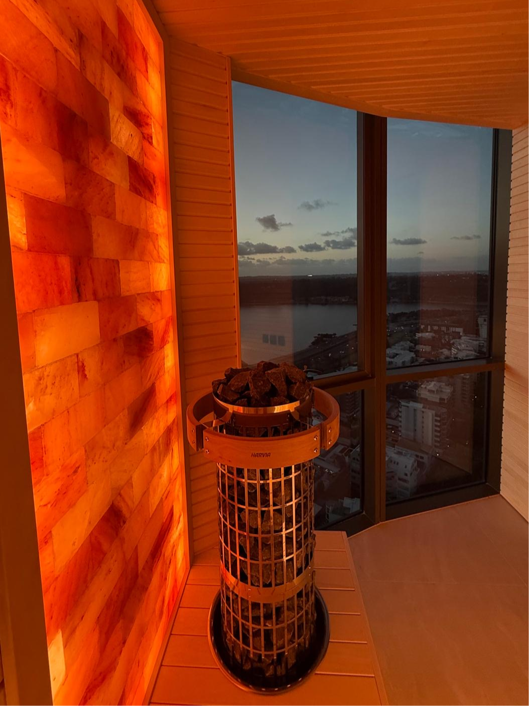 Interior of custom perth-made wooden sauna with multi-level benches and a heater filled with stones.