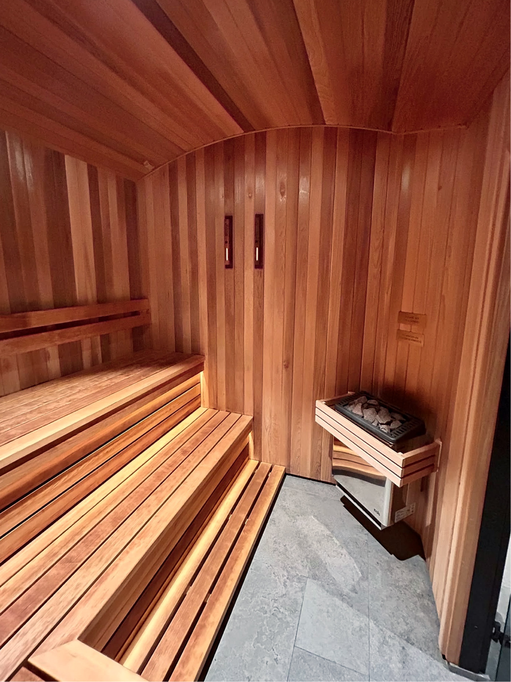 Interior of a custom sauna with glass door and wooden handle.