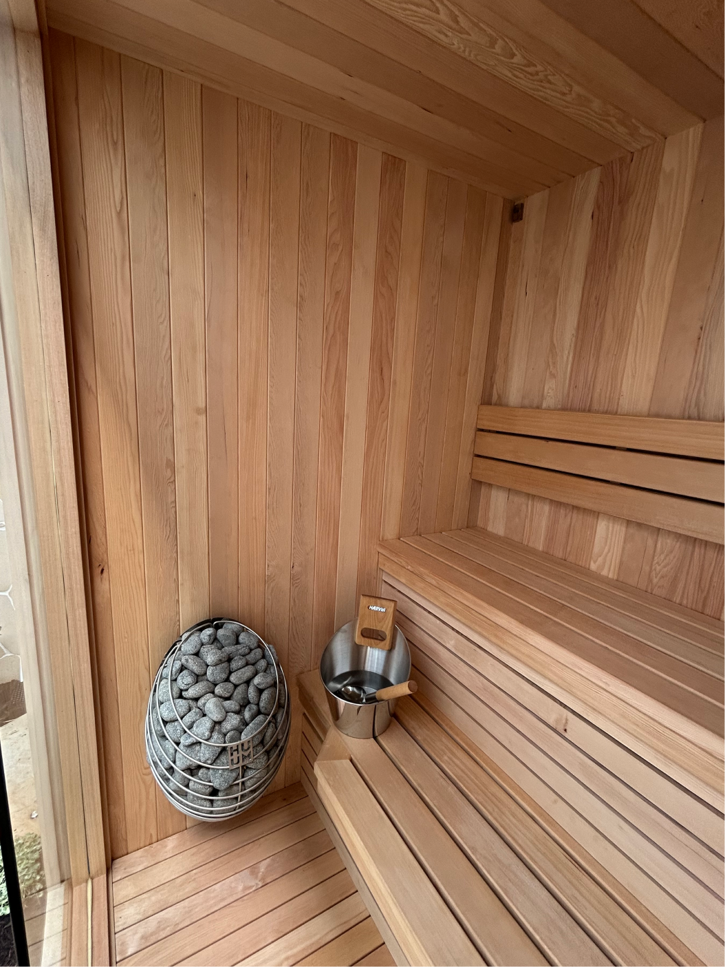 Modern wooden sauna interior with tiered bench seating and ambient LED lighting. Perth custom built sauna.