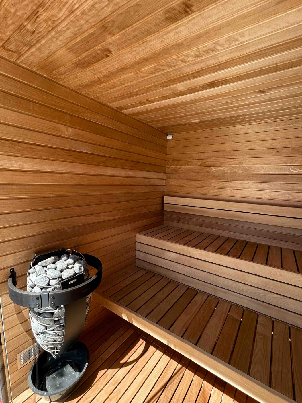 Modern wooden sauna interior with tiered bench seating and ambient LED lighting. Perth custom built sauna.