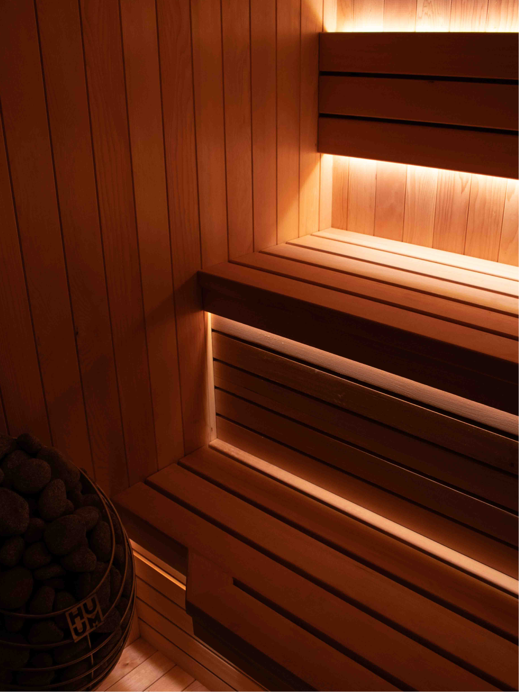 Modern wooden sauna interior with tiered bench seating and ambient LED lighting. Perth custom built sauna.