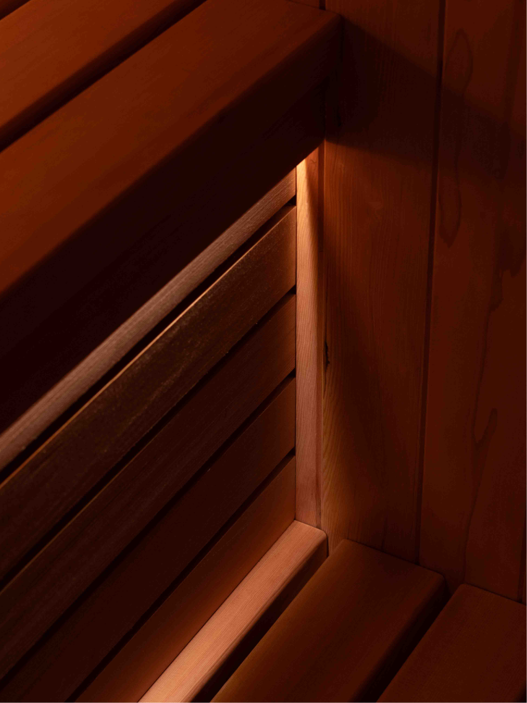 Interior of custom perth-made wooden sauna with multi-level benches and a heater filled with stones.