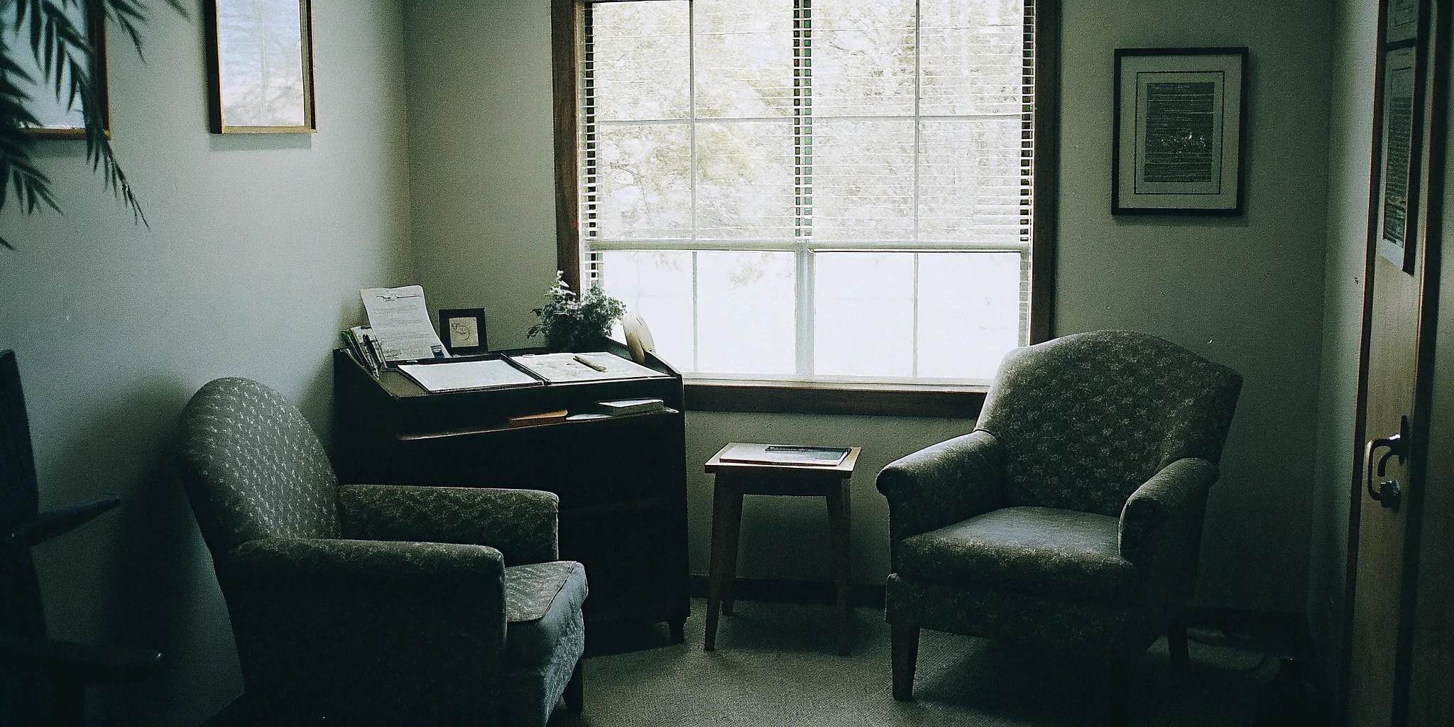 Professional mental health counselor's office with a clipboard and assessment documents on a desk, warm natural lighting