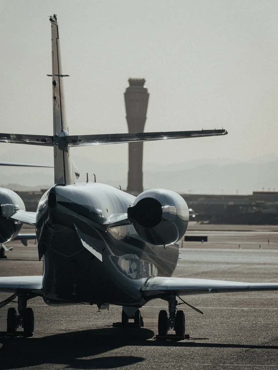 Business jet parked on the apron at dusk, control tower in the distance, business travel by Vinova Jets