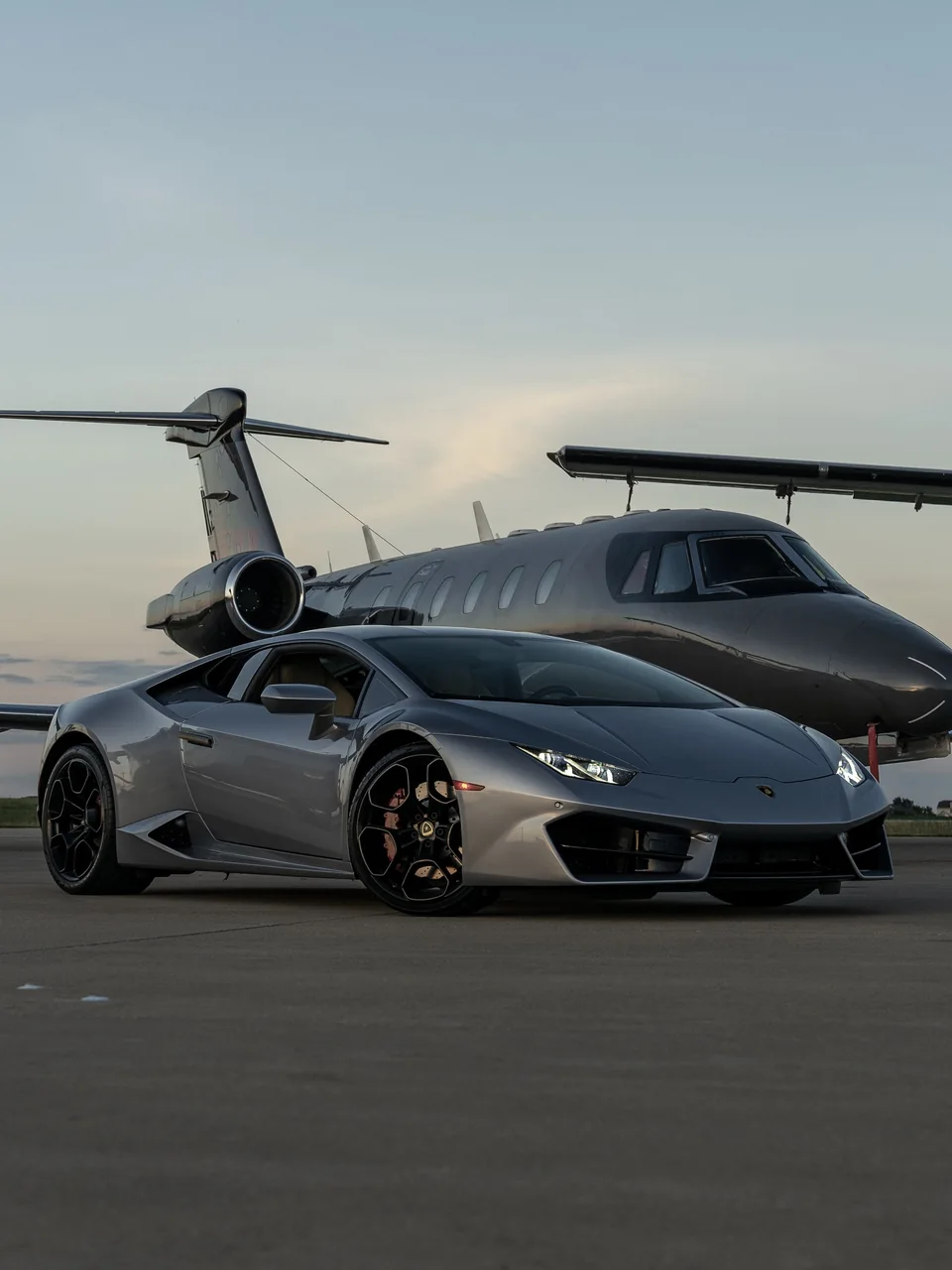 Lamborghini Huracan parked beside a private jet at sunset, leisure travel by private jet