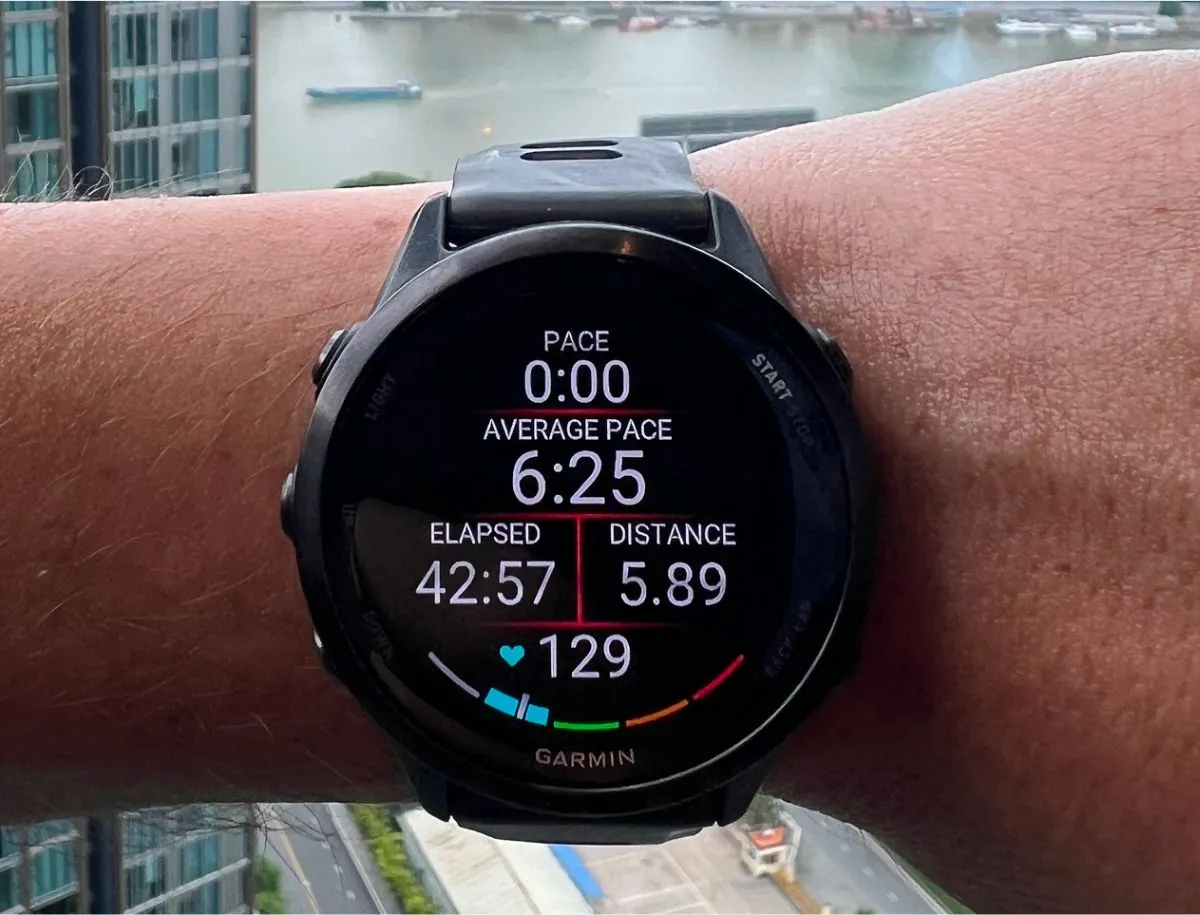 Garmin Forerunner 570 worn on wrist during a run showing 6:25 average pace, 42:57 elapsed time, 5.89km distance, and 129 bpm heart rate on the AMOLED workout data screen