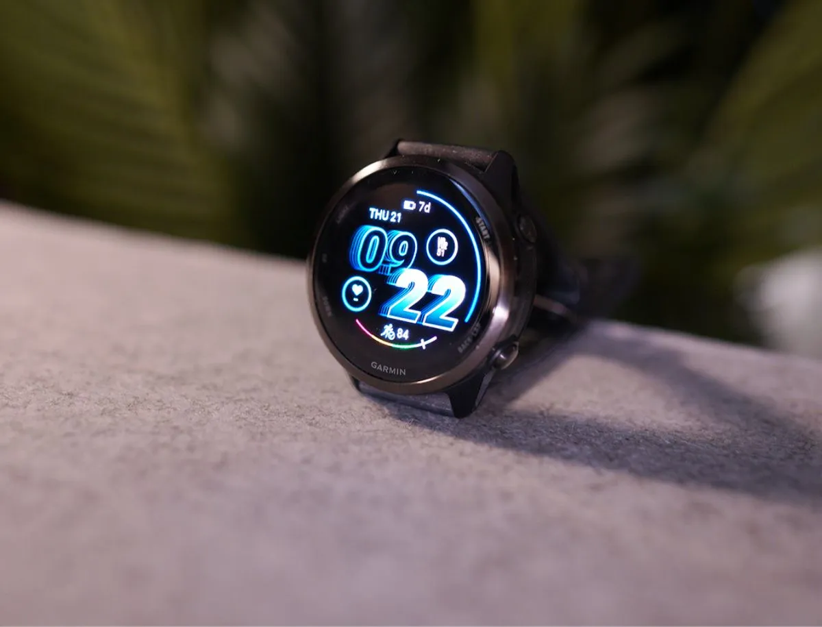 Garmin Forerunner 570 42mm in black colorway resting on a gray surface, AMOLED display showing Thursday 21st at 9:22 with 7-day battery remaining indicator and heart rate reading of 84 bpm