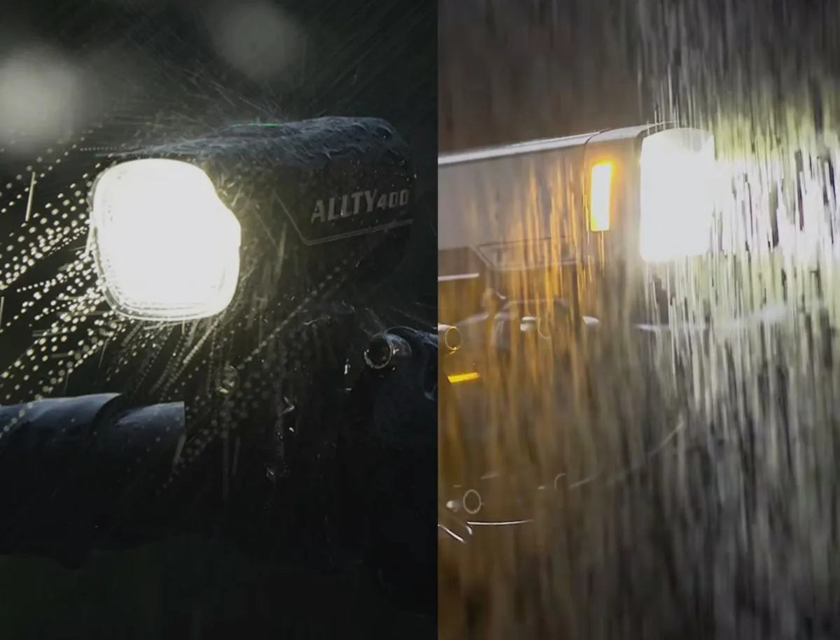 Split nighttime rain test showing the Magicshine Allty 400 on the left firing a bright white beam through heavy water droplets, and the Trek Commuter Pro RT on the right with its dual warm-toned LEDs glowing through rainfall