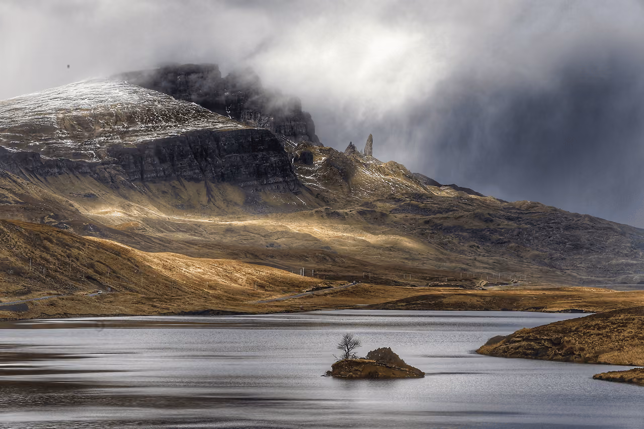Misty mountain landscape near the Old Man of Storr with a small loch in the foreground