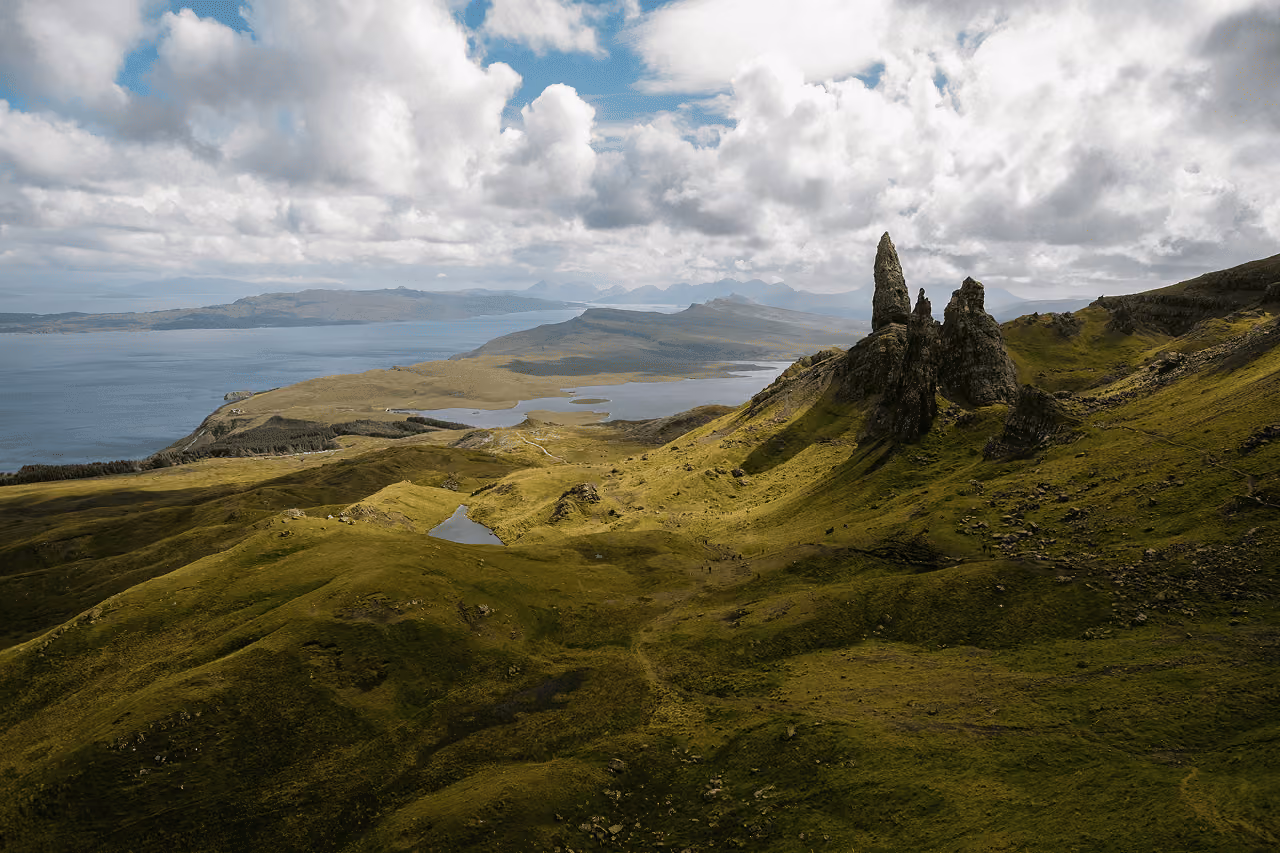 The Old Man of Storr rock spire under a cloudy sky, with the Sound of Raasay in the distance