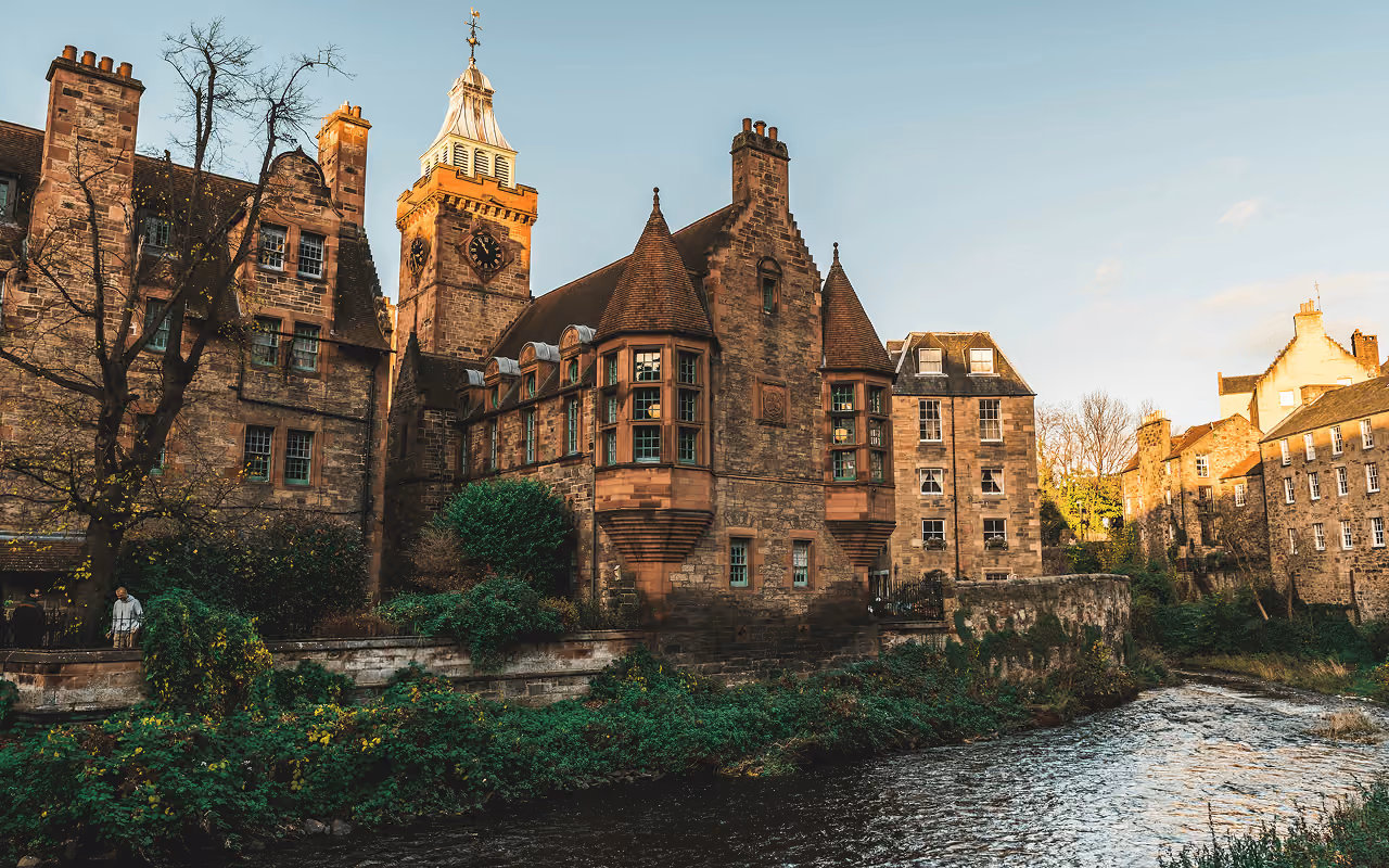Historic stone buildings and clock tower of Dean Village along the Water of Leith at golden hour