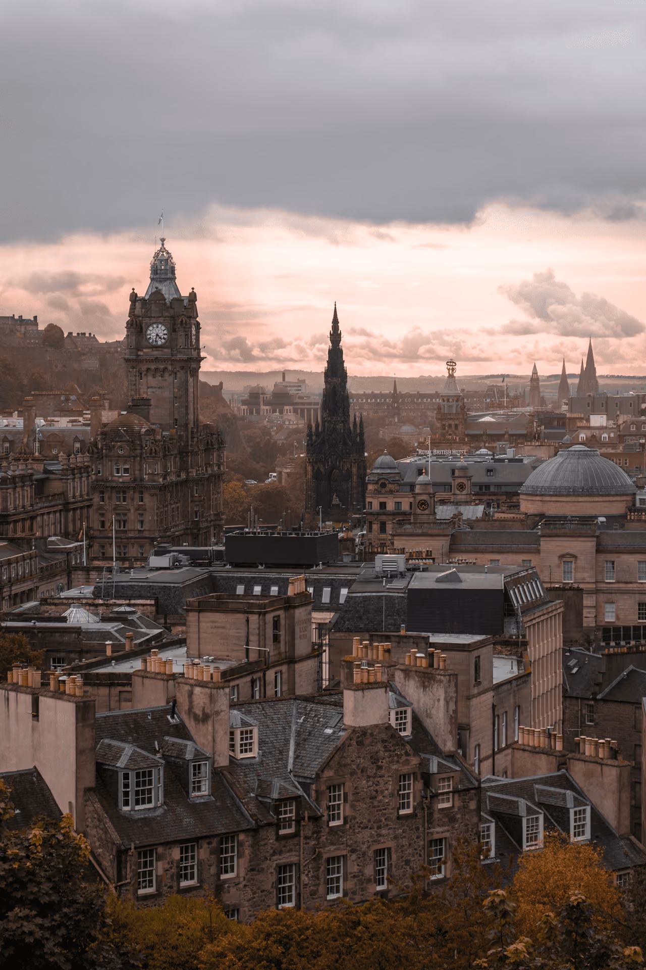 Edinburgh city skyline silhouetted at golden hour with the Balmoral Hotel clock tower rising above the rooftops