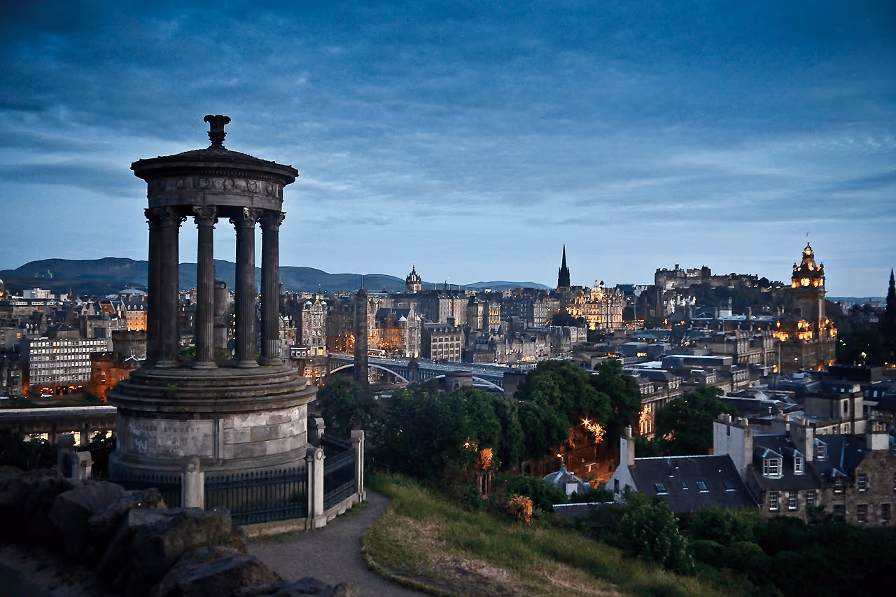 The Dugald Stewart Monument on Calton Hill with Edinburgh's illuminated skyline at dusk