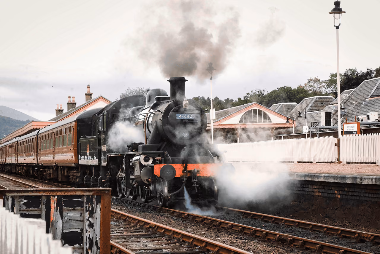 Steam locomotive 46512 billowing smoke and steam as it arrives at Aviemore station on the Strathspey Railway on a grey autumn day