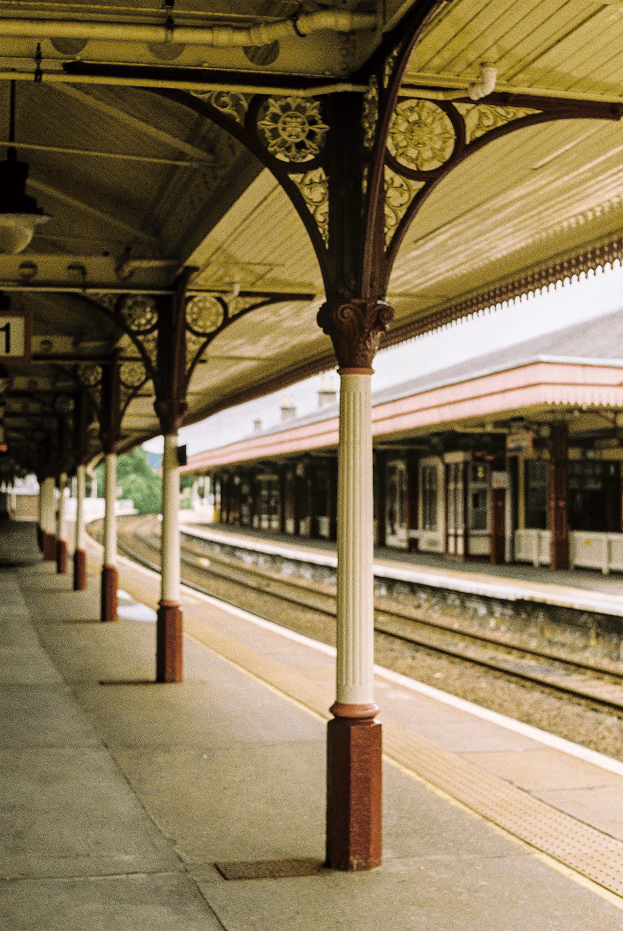The ornate Victorian cast-iron canopy columns of Aviemore railway station platform with decorative floral detailing on a quiet afternoon