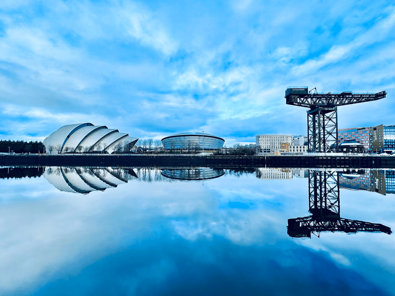 The Clyde Auditorium, SSE Hydro and Finnieston Crane perfectly reflected in the glassy surface of the River Clyde on a winter morning