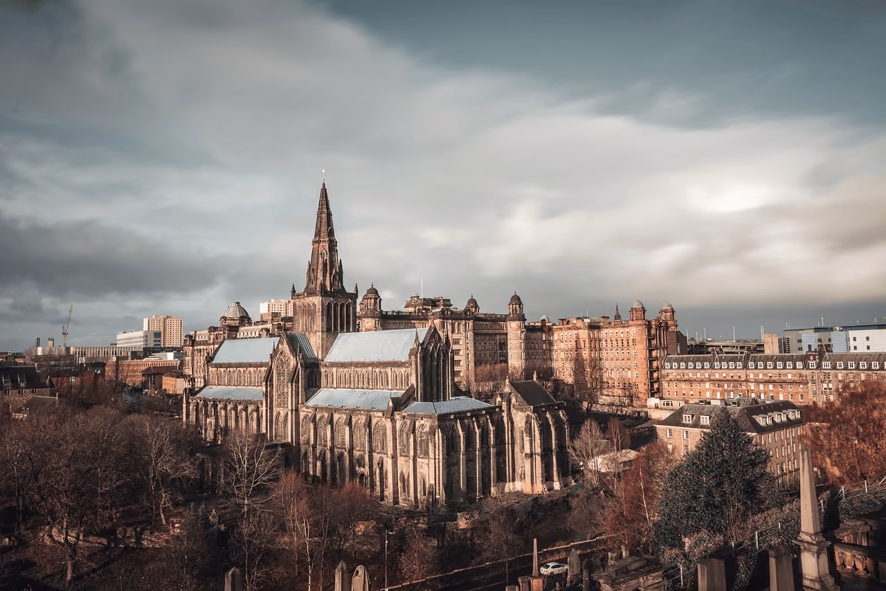 Glasgow Cathedral's soaring Gothic spire and nave rising above the winter trees on a dramatic stormy sky