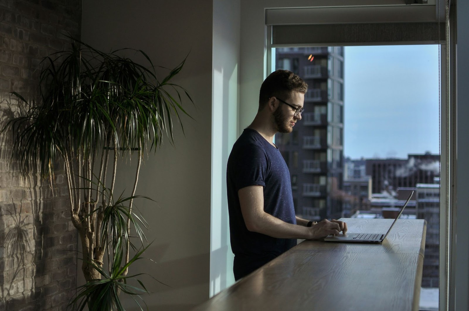 Person standing while typing on laptop