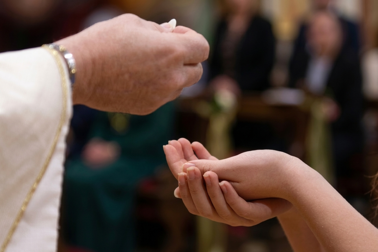 Priest pouring water from a shell onto a baby's head during baptism ceremony.