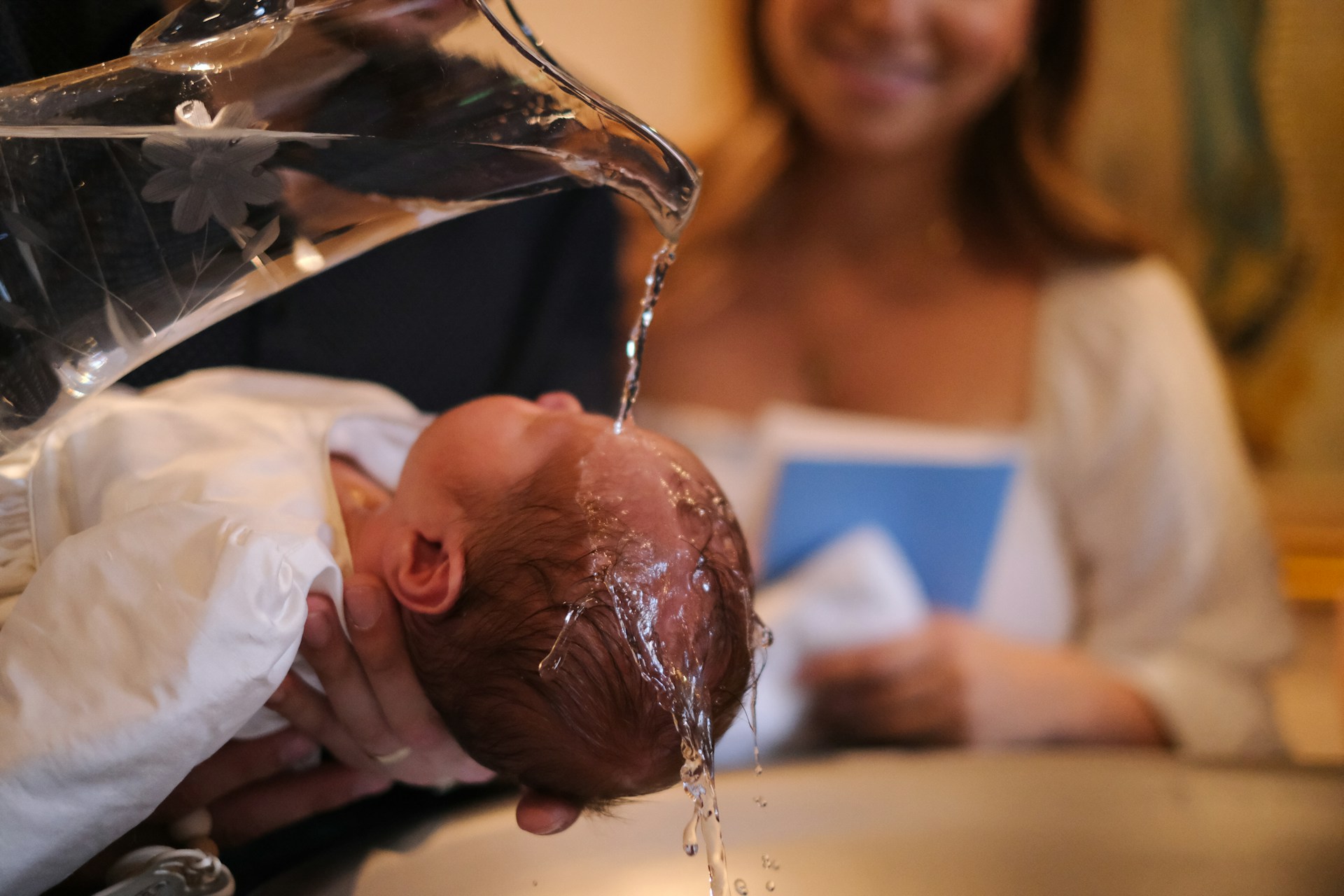 Baby's head being anointed with water from a shell during a baptism ceremony in a church.