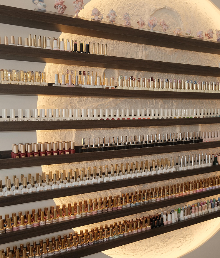 Wall shelves filled with rows of various nail polish bottles in different colors and designs.