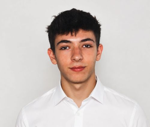 Young man with dark hair wearing a white collared shirt against light gray background.