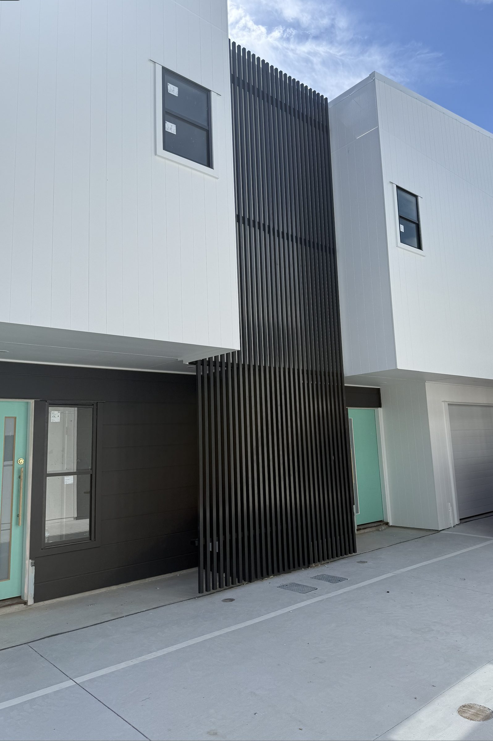 Full-height aluminium batten privacy screen between townhouses