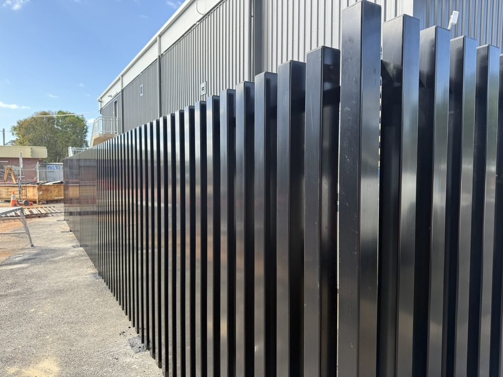 Black aluminium batten fence run to a commercial site boundary